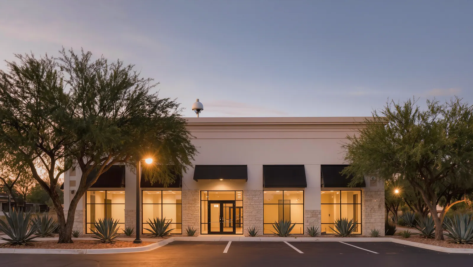 Modern commercial office building at dusk with a dome camera over the entrance