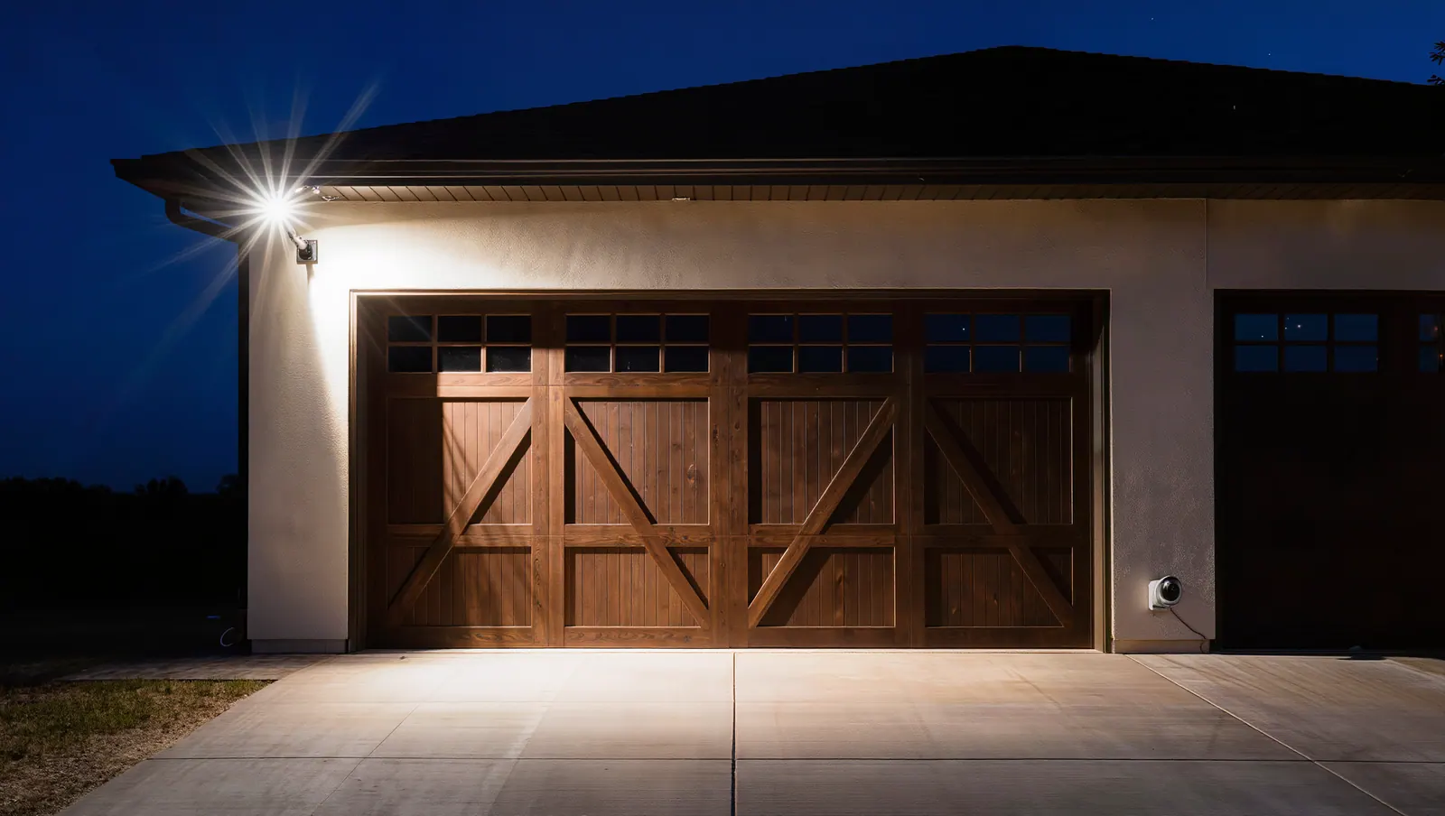 Garage and driveway lit by a motion floodlight at night