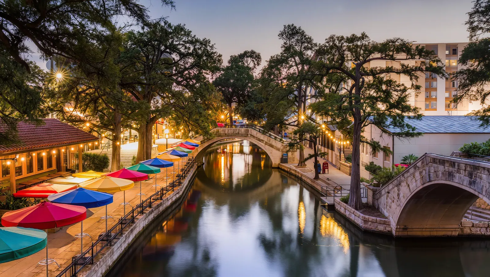 San Antonio River Walk at dusk with cypress trees and string lights